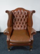 A brown button leather Chesterfield wing back armchair