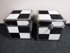 A pair of aluminium cube flight cases upholstered in a white and black checked fabric