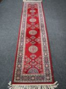 A fringed machine made Persian runner on red ground