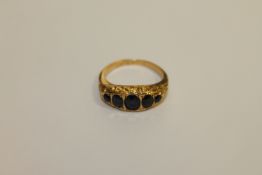 An 18ct gold ring set with five blue stones, size K, 2.9g.