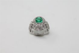 An Art Deco style emerald and diamond cluster ring, an octagonal cut emerald set to a pierced,