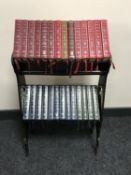 An oak Arts and Crafts two tier book trough containing twenty seven leather bound readers digest