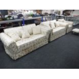 Three piece Delcor lounge suite in cream and gold fabric with scatter cushions and a footstool