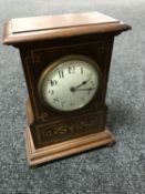 A Victorian inlaid mahogany mantel clock with enamelled dial on brass feet