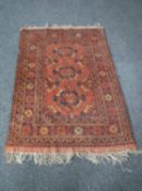 A fringed Persian rug of geometric design on red ground
