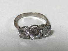 An 18ct white gold three stone dress ring, size N.