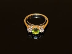 A peridot and diamond three stone ring