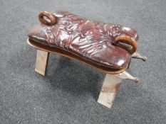 A 20th century camel stool with button leather cushion