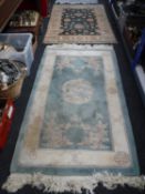 A fringed Chinese rug with dragon decoration on green ground and one other