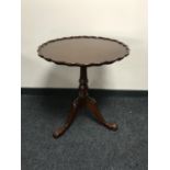 A mahogany pie crust edge tilt topped table on three way pedestal