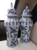 A pair of blue and white glazed pottery lidded urns with floral decoration,