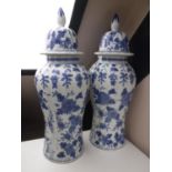 A pair of blue and white glazed pottery lidded urns with floral decoration,