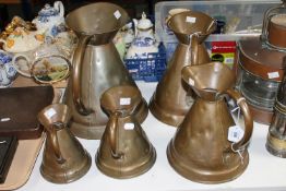 Six graduated copper jugs