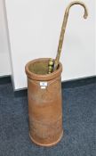 An earthenware stick pot containing a Victorian fire poker and a walking stick with various badges