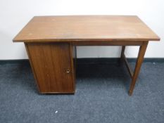 A mid 20th century teak desk fitted with a cupboard pedestal