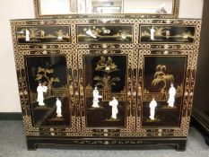 A Japanese lacquered triple door sideboard with mother of pearl figures