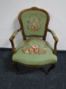 An antique style walnut armchair with floral cushions