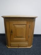 An antique style light oak corner cabinet