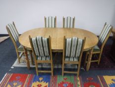 A light oak extending dining table and six chairs upholstered in striped fabric