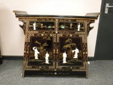 A Japanese lacquered two drawer side table with mother of pearl figures