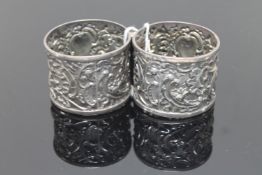 An ornate pair of silver napkin rings with putti playing drums (2)