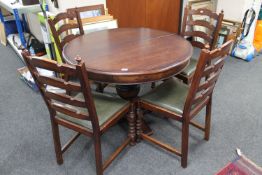 A heavy oak circular extending table on pedestal support and four ladder back chairs