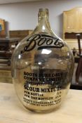 A large glass demijohn with Boots advertising