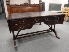 A mahogany flap sided library table fitted five drawers and inset leather panel