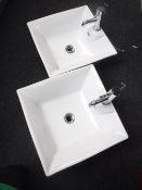 A pair of white ceramic hand basins with taps