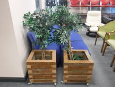 A pair of heavy square wooden planters containing artificial plants