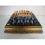 A chess board on gilt base with dragon pieces together with a boxed set of vintage dominoes