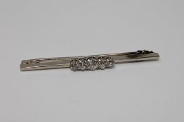 An 18ct white gold and platinum set five stone diamond bar brooch, approximately 0.7ct, 5.2g.