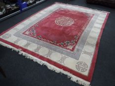 A large fringed embossed Chinese carpet on pink ground