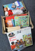 Two boxes containing assorted board games, Giles annuals, dolls,