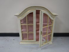 A cream and gilt double door wall mounted curio cabinet