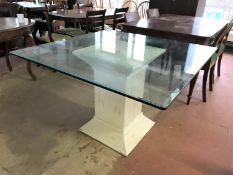 A contemporary glass topped dining table on wicker pedestal