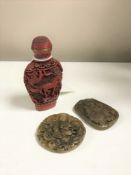 A Chinese cinnabar scent bottle and two carved soapstone pendants