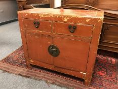 An Oriental style red lacquered side cabinet,