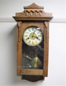 An early 20th century oak cased wall clock with enamelled dial,