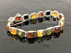 A white metal bracelet set with amber coloured panels