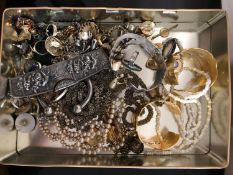 A tin of costume jewellery, brooches,