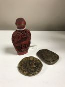 A Chinese cinnabar scent bottle and two carved soapstone pendants