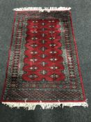 A fringed Bokhara design rug on red ground,