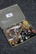 A tin of costume jewellery,