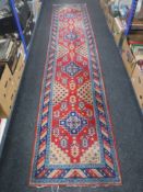 An Eastern carpet runner on red ground,