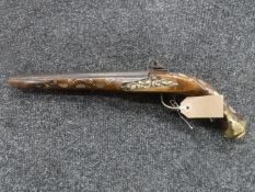 A replica flintlock pistol with mother of pearl inlay