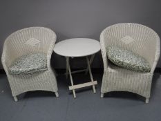 A pair of white loom armchairs and a folding Ikea table