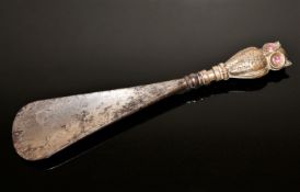 An Edwardian shoe horn with silver handle in the form of an owl with ruby set eyes,