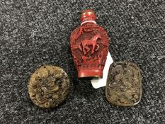 A Chinese cinnabar scent bottle and two carved soapstone pendants