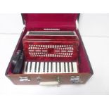 Piano accordion in marbled red, unbranded, in carry case.